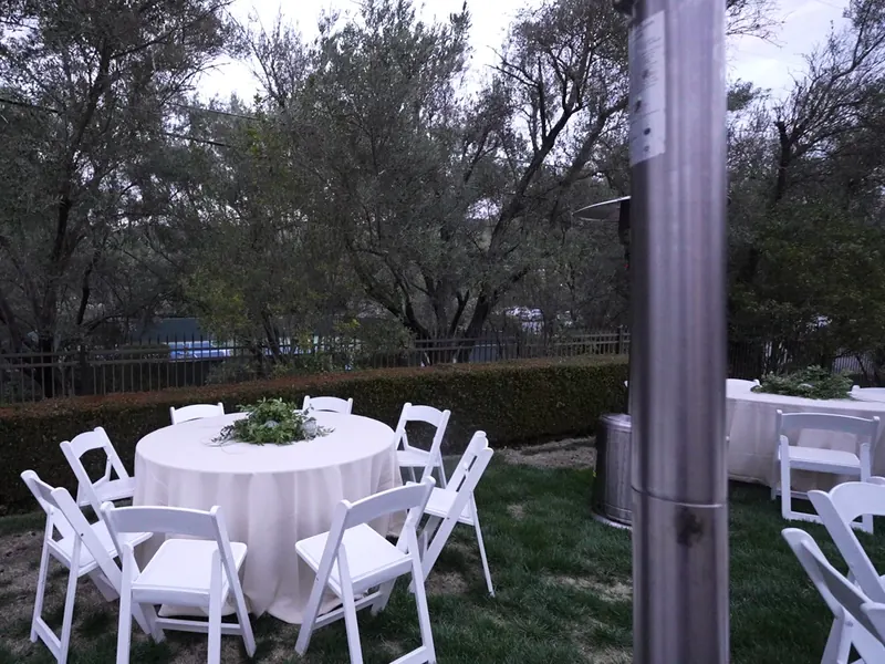 Catering San Francisco — linened round table with white folding chairs and a greenery centerpiece at a garden reception