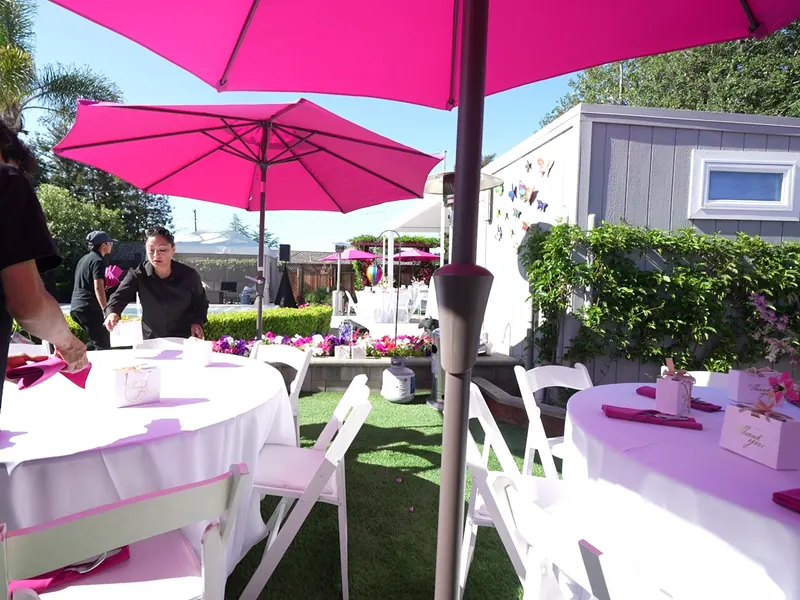 Catering staff finishing table settings under shade umbrellas at a Daly City backyard event
