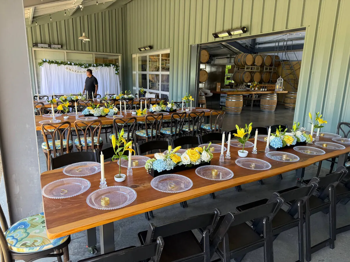 Low floral centerpieces with hydrangea, roses, and taper candles running down a long San Francisco banquet table by SF Catering Company